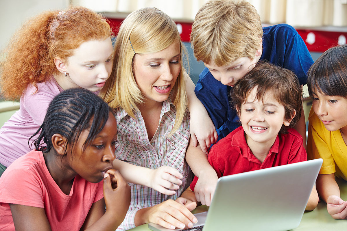 Children and teacher around laptop