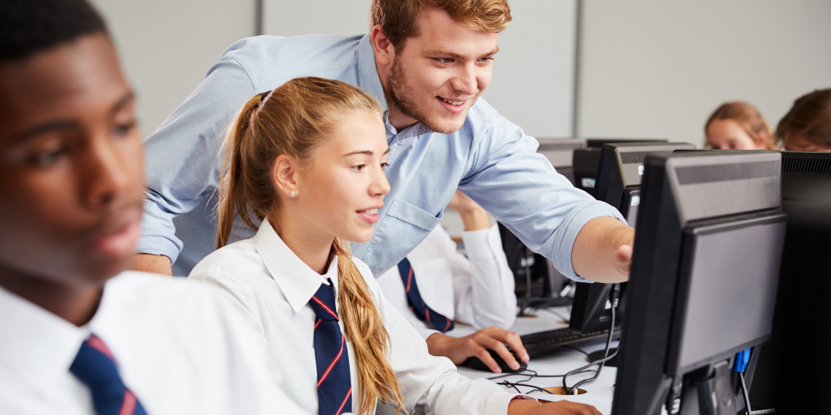 Teacher supporting student on computer